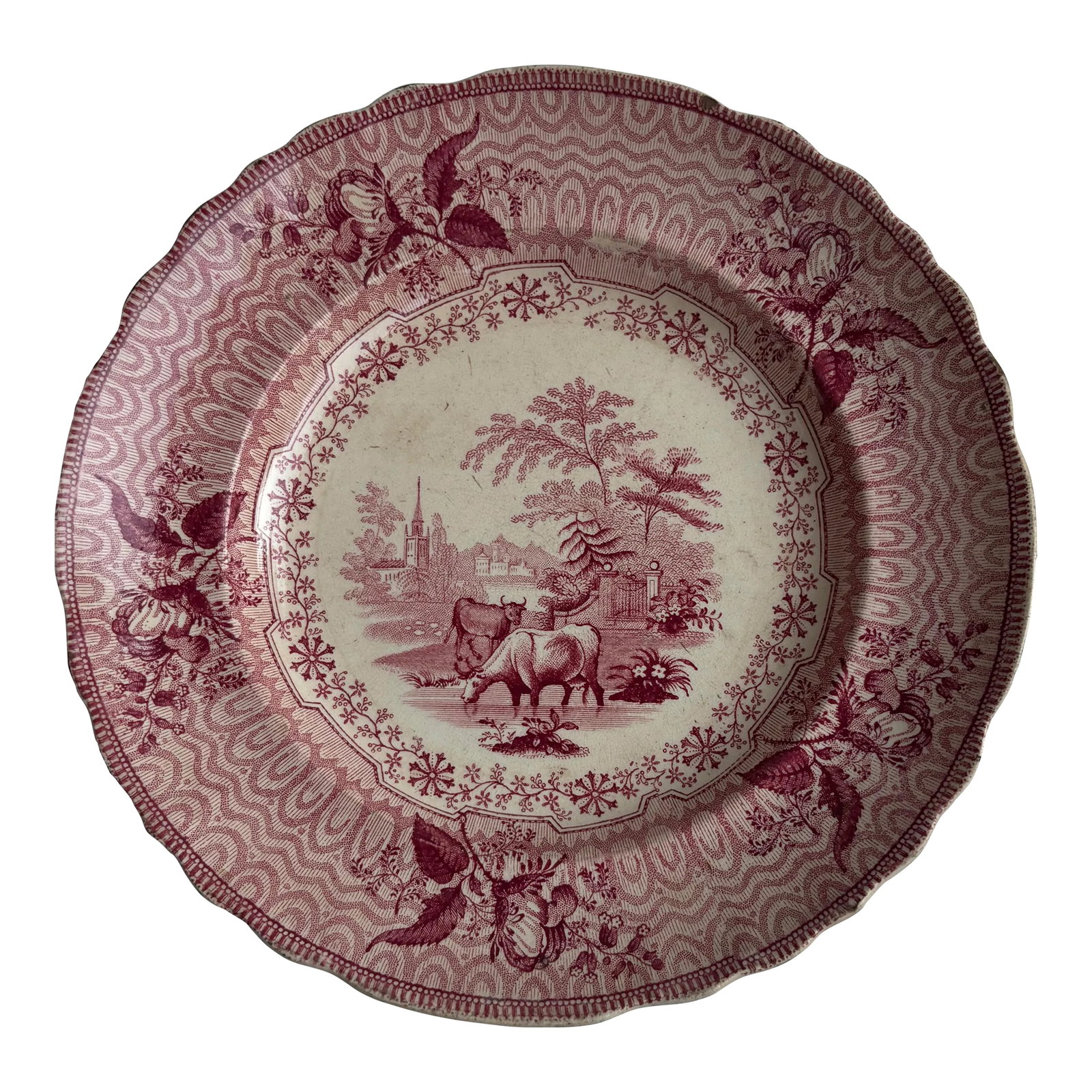 English Transferware Plate in Red With "Park Scenery" Pattern: English transferware plate in red with "Park Scenery" pattern by Phillips pottery. Bordered with rosebuds the scene depicts cattle. The Phillips pottery was founded by 22 and 20 year old brothers,
