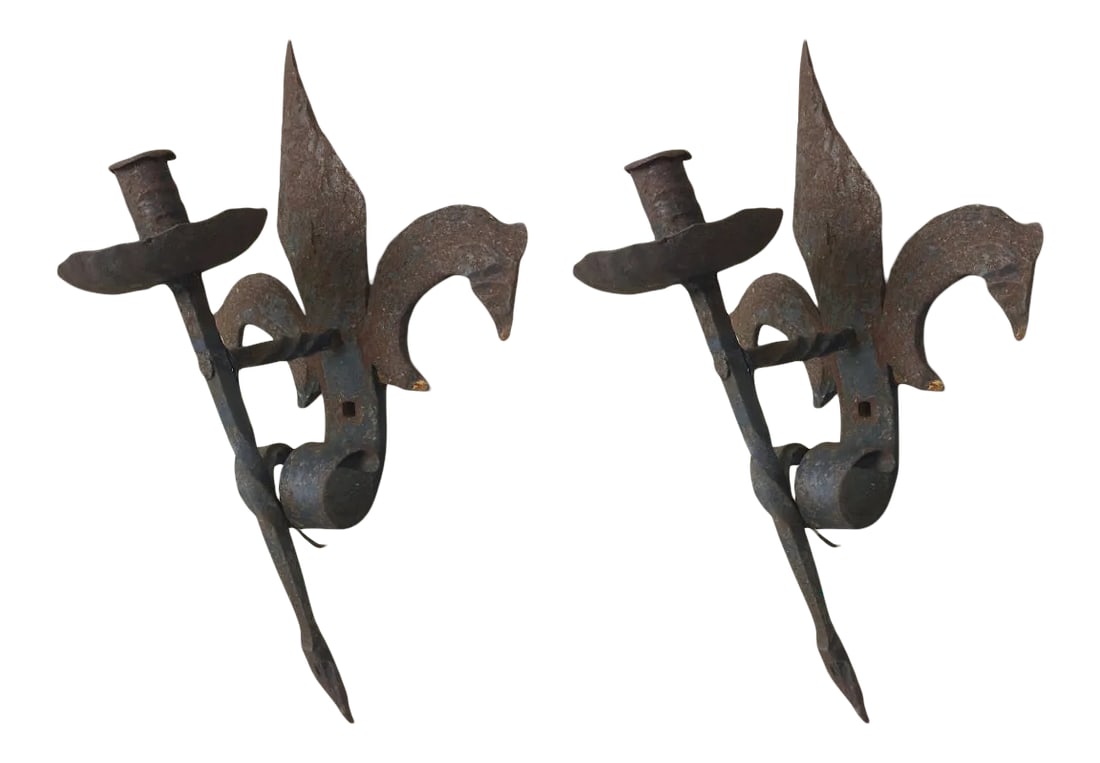 19th Century French Forged Iron Fleur De Lis Torchere Sconces - a Pair: A solid pair of French forged iron Fleur de Lis Torchere sconces that evoke the old-world charm of a small village in the French countryside. In some ways, they are medieval and one can imagine them
