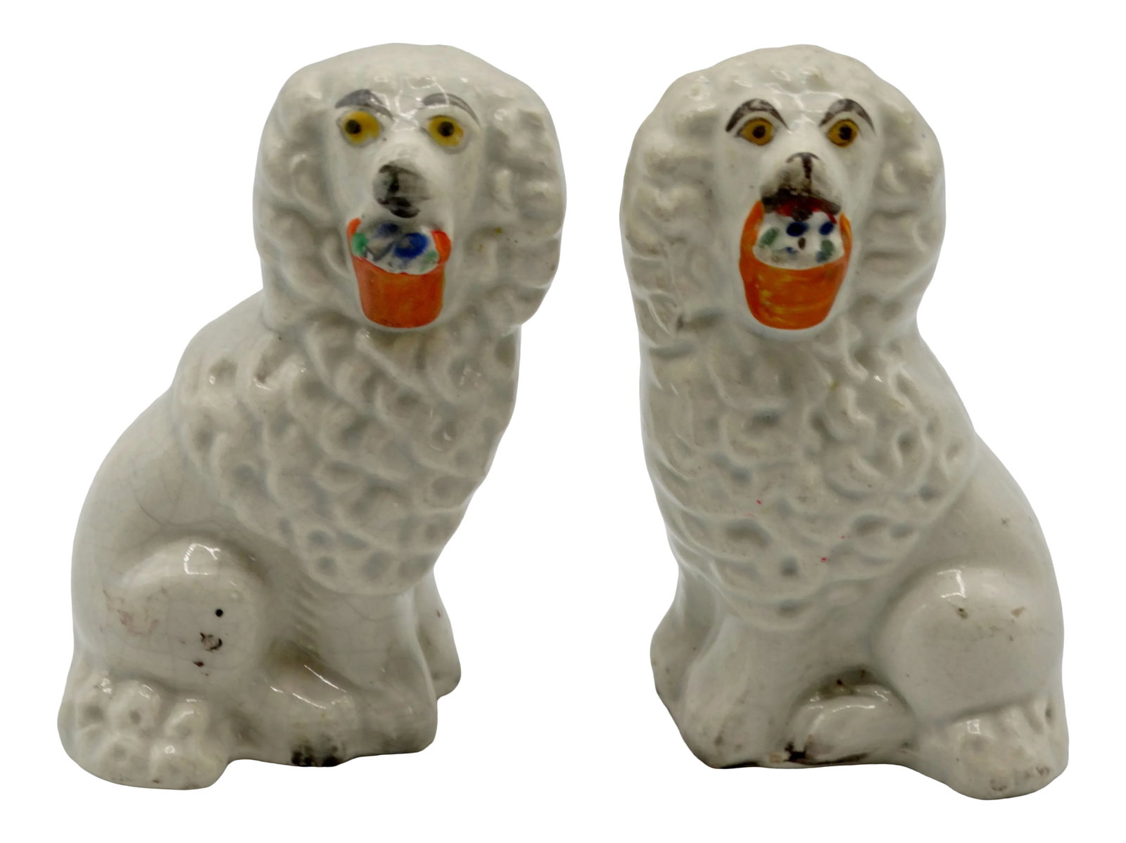 Antique English Staffordshire Dogs With Baskets, a Pair: 19th-Century English Staffordshire spaniel dogs each with a basket in his mouth. They are hand molded and hand painted with very nice detail and date to the mid to late Victorian era. . They are unmar