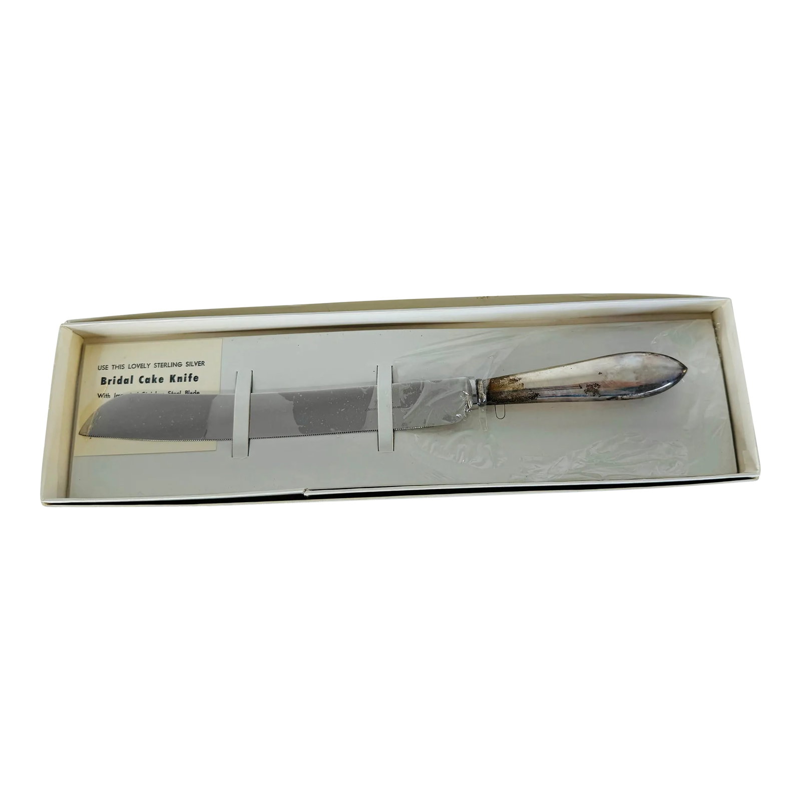 Vintage 1960s Sterling Silver Serrated Cake Knife: Vintage 1960s Sterling Silver Serrated Cake Knife. The knife is still in the original box and original wrapping. Marked. Condition: Alterations: Original Condition Unaltered Imperfections: Some