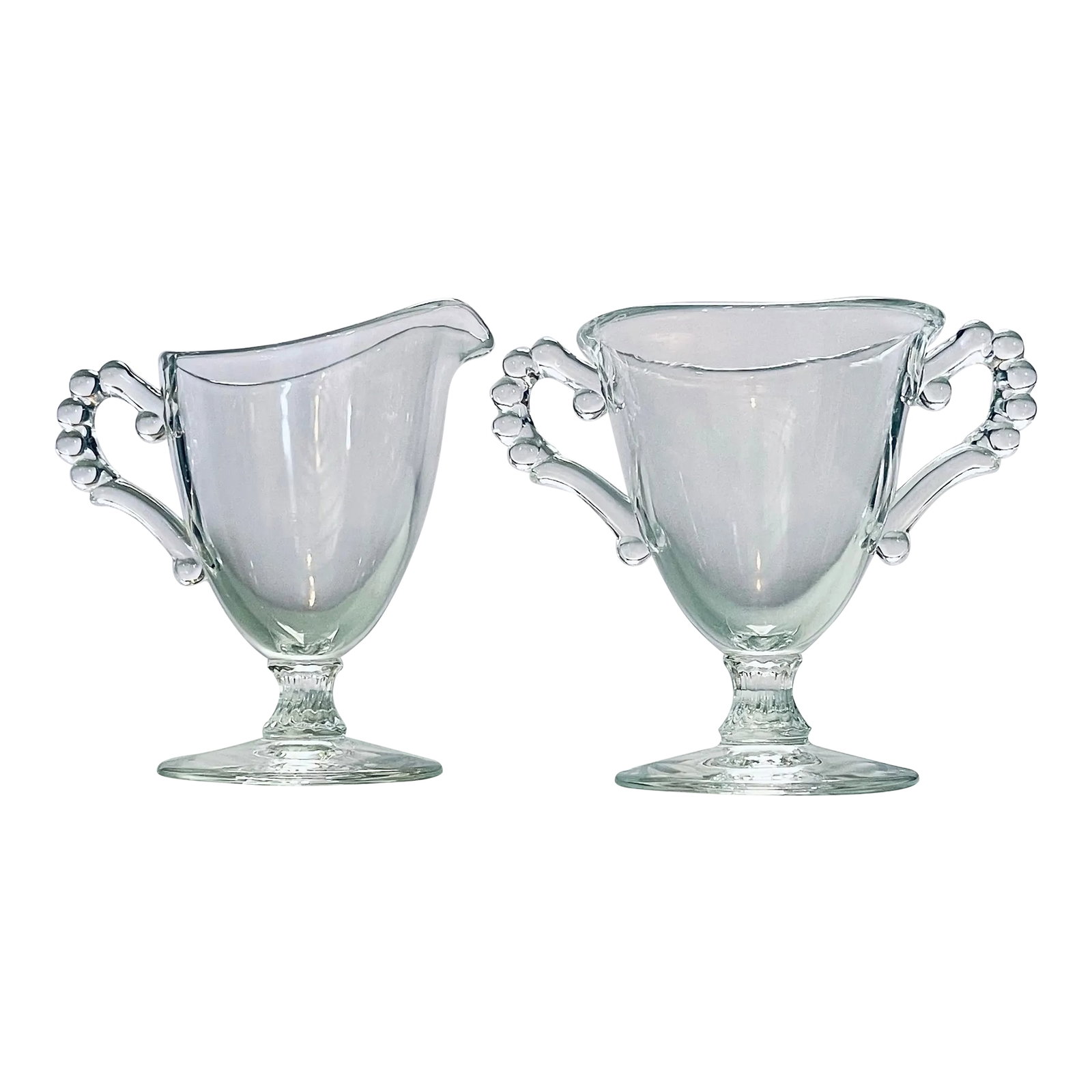1930's Candlewick Footed Creamer & Sugar Bowl: An elegant cream and sugar set in clear glass with fluted stem and beaded handles. Made by the Imperial Glass Company in Bellaire, Ohio. -Creamer measures 4 1/2 inches from handle to spout, 4 3/4