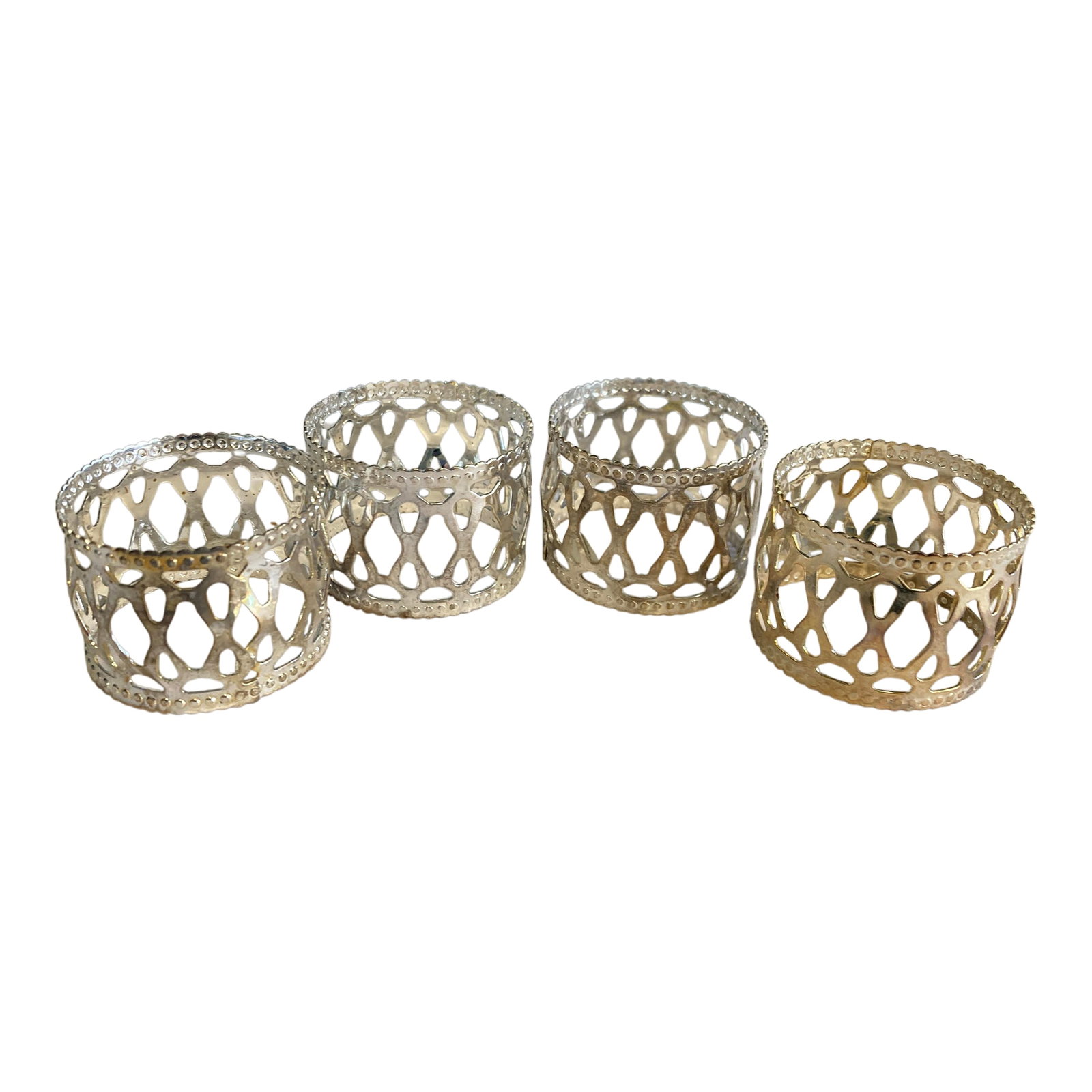 Vintage Silverplate Openwork Napkin Rings - Set of 4: his set of vintage silverplate napkin rings showcases an intricate openwork design accented with beaded edges. The pierced metal construction creates a light, elegant appearance that complements both