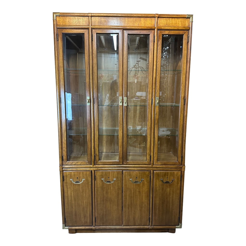 Drexel Campaign China Cabinet Accolade Collection: This is a vintage Drexel Heritage Campaign style china cabinet from the Accolade Collection. It features a medium-tone finish with glass-paneled doors on the top and wood-paneled doors on the bottom.