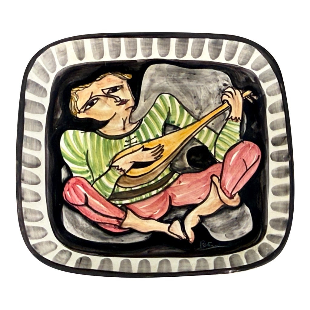 Vintage Italian Mid Century Giovanni Petucco Italian Ceramic Wall Plaque With Troubadour Figure: This mid century Italian ceramic wall plaque was created by Giovanni Petucco. The piece features a hand painted troubadour or minstrel figure playing a stringed instrument against a black background. 