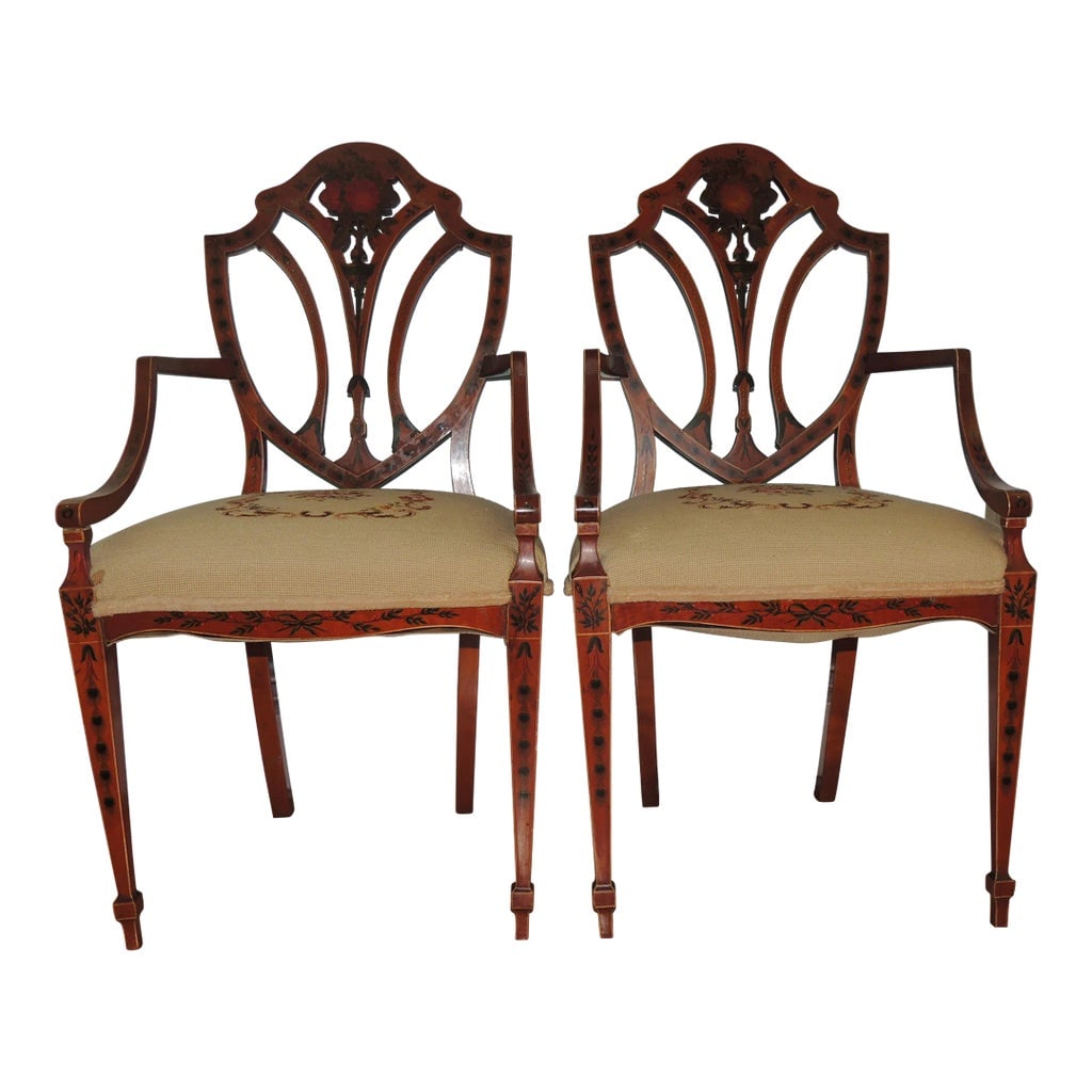 Early 20th Century Antique Adam Style Painted Shield Back Armchairs - Set of 2: These antique Adam-style open armchairs will dominate the area wherever they are placed. Boasting one of the most iconic chair designs, they feature lovely floral designs painted on the satinwood back