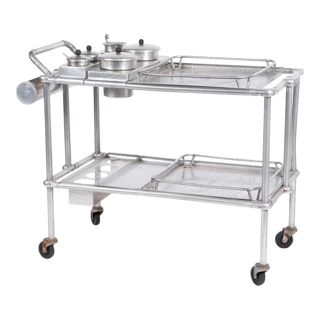 Russel & Mary Wright for Everlast Patio or Bar Cart: American, 1940s, aluminum hand-wrought and tubular construction cart with lift-out trays of foliate motifs, and inset accoutrements, on wheels, trays stamped "Hand Forged Everlast Metal". The accoutre