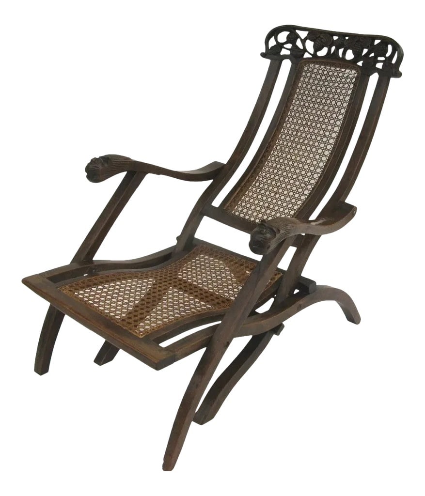 Indo-Portuguese Carved Folding Cane Chair: Indo-Portuguese carved walnut folding chair, early 18th century, an ornately carved piece with floral motifs in a scrolling fashion arm supports terminating in carved canine heads. Beautiful color.