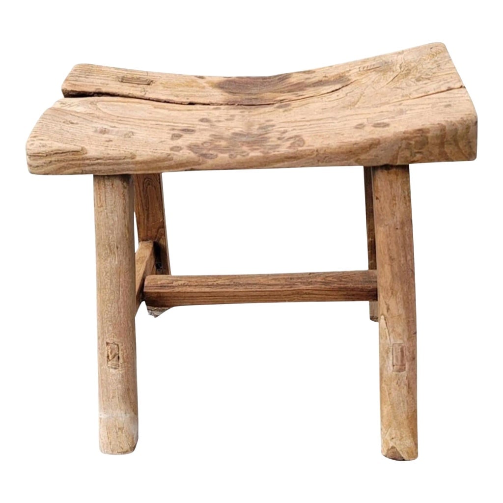 19th Century Chinese Elm Rustic Primitive Brutalist Stool: Dated to mid 19th century, this rustic, farmhouse, primitive and brutalist stool has simple splayed-leg design and well-worn finish. Crafted of northern elm wood with mortise-and-tenon joinery, withou