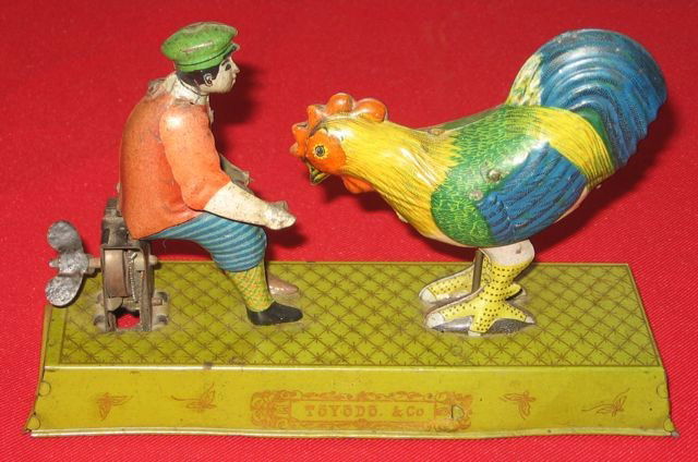 Toyodo Japanese Painted Tin Wind-up Toy: Title: Japanese Toyodo painted wind-up tin toy. Maker: Toyodo & Co. Date: Unknown. Size: 4 ½” x 7 ¼” x 2 ¼” (11.4 x 18.4 x 5.7 cm). Description: Man Feeding a Chicken.