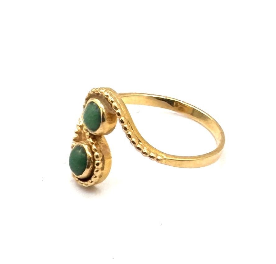 A TURQUOISE "TOI ET MOI" RING Designed as a twin-stone bypass ring in 18k gold: A charming and vibrant "Toi et Moi" (You and Me) ring, featuring two circular cabochon turquoises of matching robin's-egg blue hue. Each stone is securely set within a polished bezel mount,