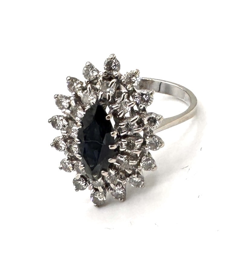 A SIGNIFICANT SAPPHIRE AND DIAMOND DOME RING A bold "Bombe" inspired statement in 18k white gold: An architectural and high-impact dress ring, masterfully crafted in 18k white gold (750/1000). The design features a dramatic, domed silhouette centered upon a vibrant oval-cut blue sapphire. The sapp
