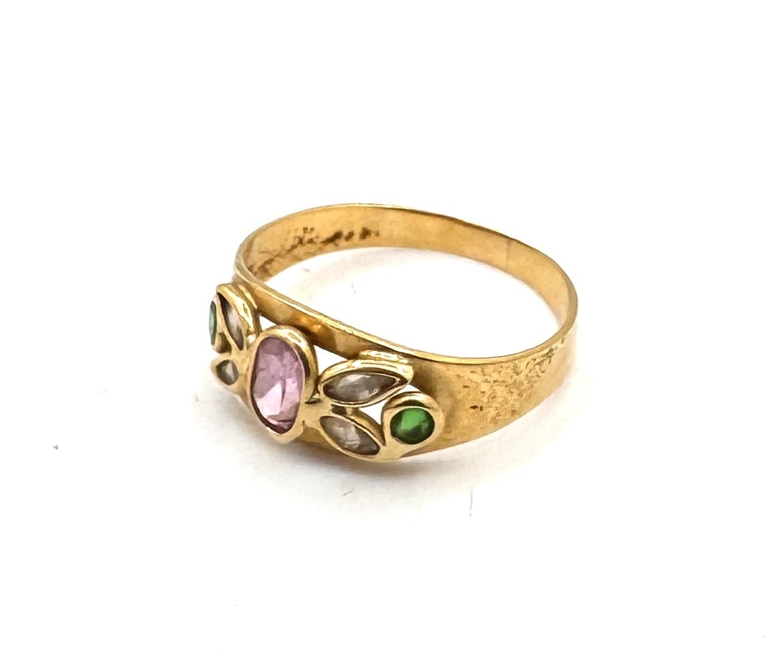 AN AMETHYST, EMERALD AND DIAMOND DRESS RING A vibrant "Jardin" style cocktail ring in 18k gold: An exquisitely colorful cocktail ring featuring a prominent cushion-cut amethyst of deep violet saturation, held within a classic four-prong setting. The central stone is elegantly flanked