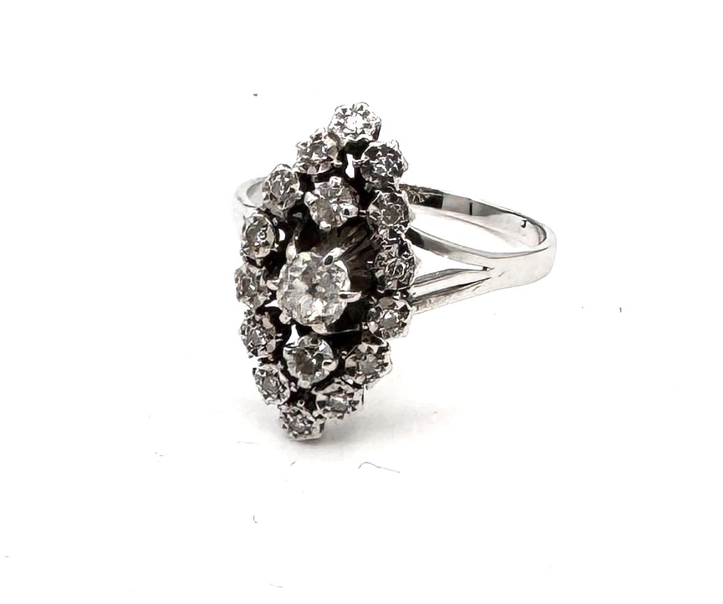 A DIAMOND "MARQUISE" CLUSTER RING A classic elongated statement ring in 18k white gold: An impressive and elegantly proportioned "Marquise" cluster ring, masterfully crafted in 18k white gold (750/1000). The design features a prominent central round brilliant-cut diamond weighing approxi