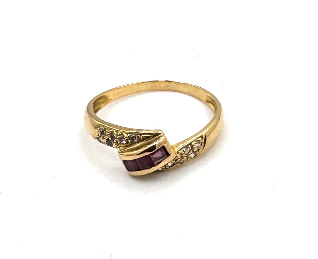 A RUBY AND DIAMOND CLUSTER RING Of traditional floral design, set in 18k gold: An elegant gemstone ring designed as a stylized floral cluster. The centerpiece features a round-cut ruby of vibrant red hue, securely held within a multi-prong setting. This central stone