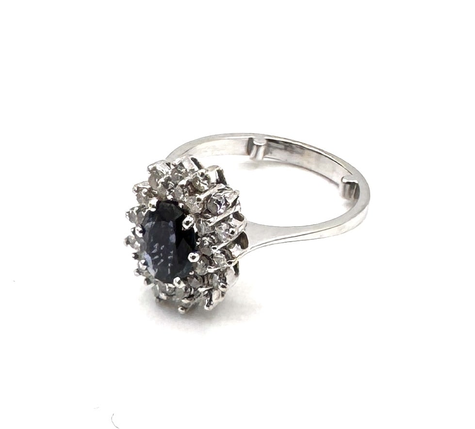 A FINE SAPPHIRE AND DIAMOND DRESS RING A classic tiered cluster design in 18k gold: An impressive and classical gemstone ring, designed as a structured oval-shaped cluster. The centerpiece features a vibrant oval-cut blue sapphire, prominently held within a multi-prong setting.