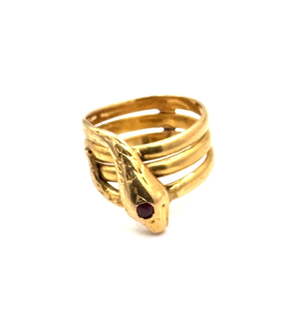A RUBY-SET "SERPENT" COIL RING A bold zoomorphic statement in 18k gold: An impressive and substantial "Serpent" wrap ring, masterfully crafted in 18k yellow gold (750/1000). This piece features a dual-coil design, with the body of the snake meticulously textured to simula