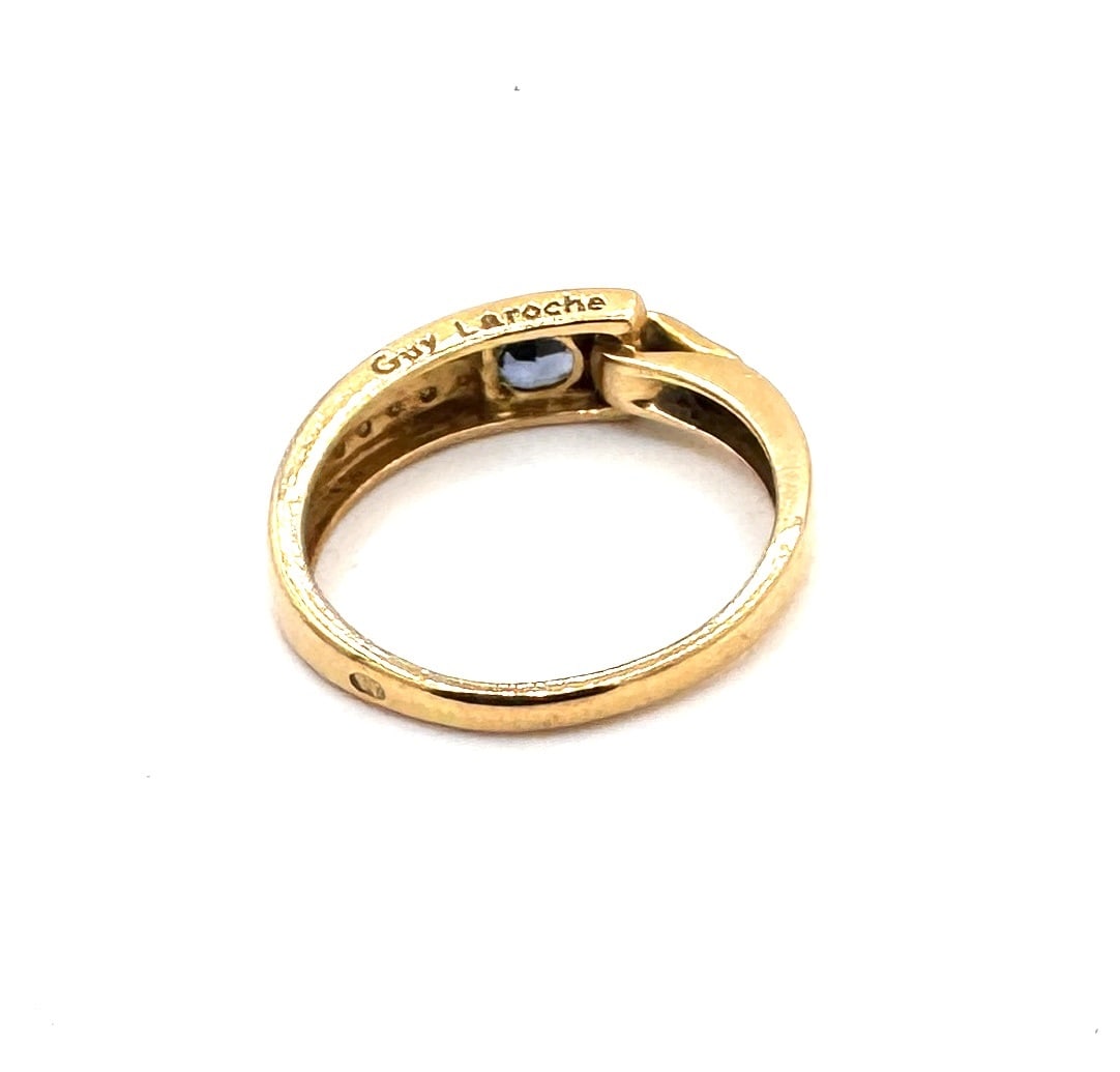 A SAPPHIRE AND DIAMOND BAND RING, BY GUY LAROCHE A sophisticated bi-color "Crossover" design in 18k: An elegant designer band ring by the renowned French couturier Guy Laroche. The piece features a stylized crossover motif, masterfully blending contrasting textures and precious materials.