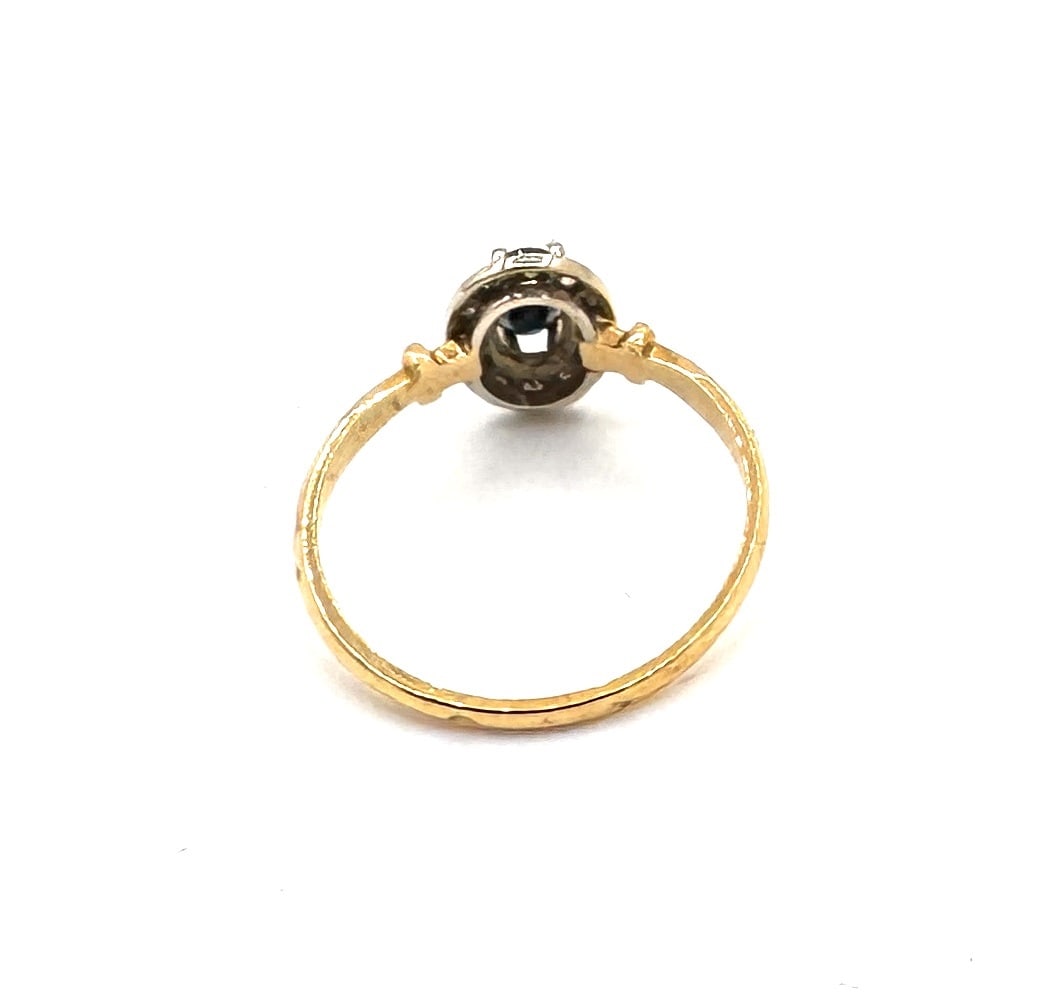 A SAPPHIRE AND DIAMOND CLUSTER RING Classic "Halo" design in 18k bicolor gold: Centering upon an oval-cut sapphire of deep saturation, held within a traditional four-prong setting. The central stone is framed by a surround of round brilliant-cut diamonds, meticulously