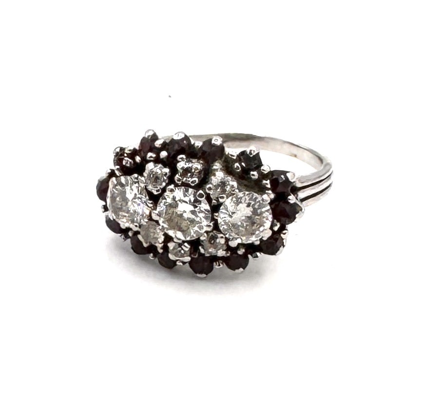 A SIGNIFICANT GARNET AND DIAMOND CLUSTER RING A bold "Trilogy" inspired design in 18k gold: A magnificent and substantial dress ring, masterfully crafted in 18k yellow gold (750/1000). The design is centered around three graduating oval-cut garnets, possessing a deep, saturated wine-red hue.