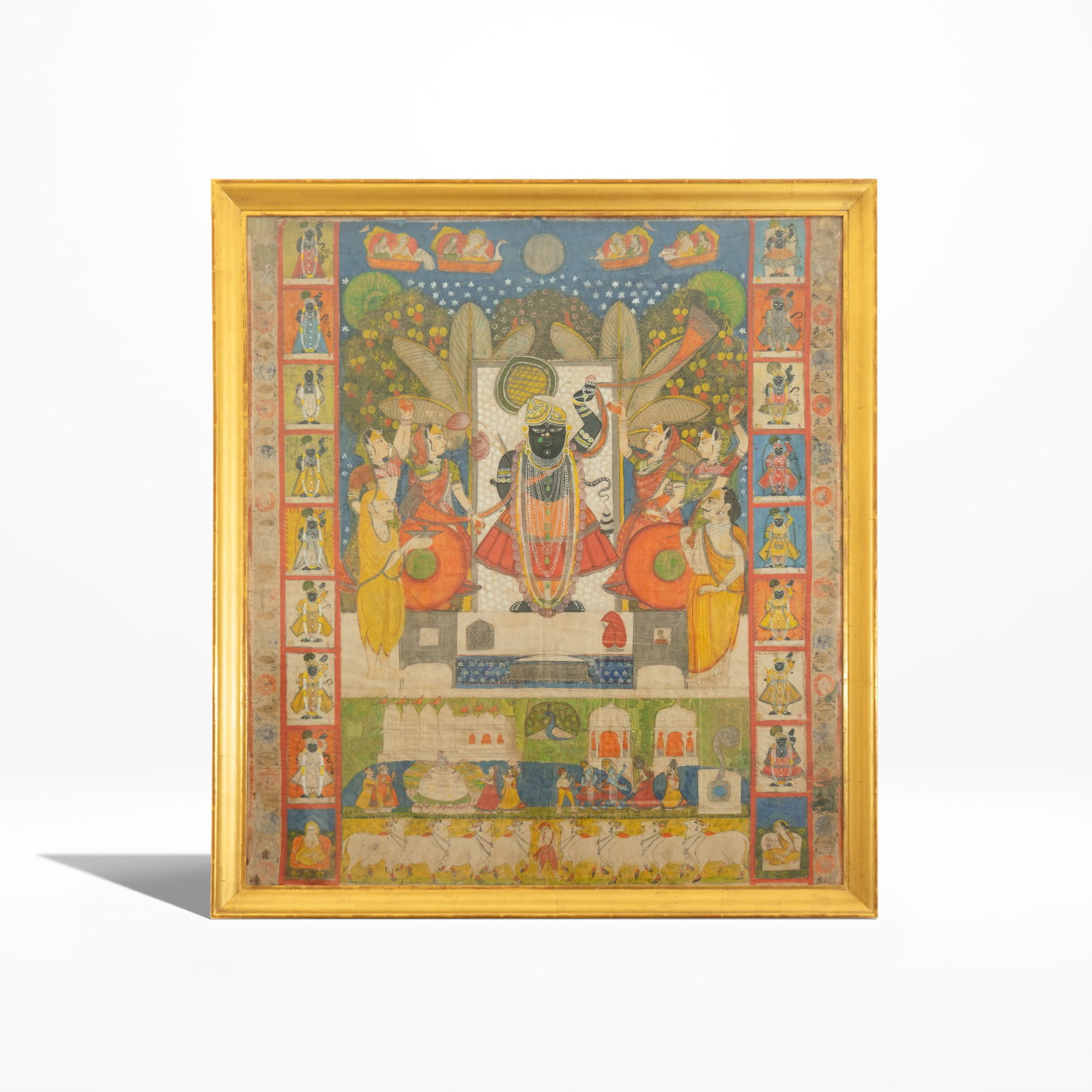 Devotional Pichwai with Swaroops Nathdwara, early 19th Century: Natural pigments on cloth This vibrant pichwai depicts Shrinathji, a manifestation of the Hindu god Krishna as a seven-year-old child. His left arm is raised, depicting him lifting Mount Govardhana to