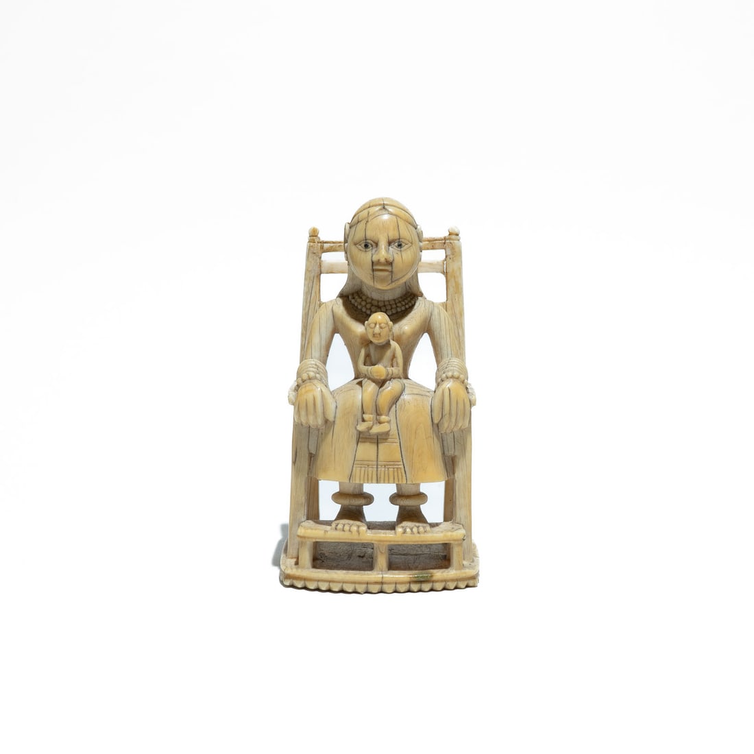 An Indian Ivory carved figure of a Holy Mary with Baby Jesus seated on chair 17th/18th Century, Goa: It represents a fascinating fusion where European Christian themes were reinterpreted through the lens of Indian craftsmanship. The Virgin's face has a distinctively oval shape with heavy-lidded, almo