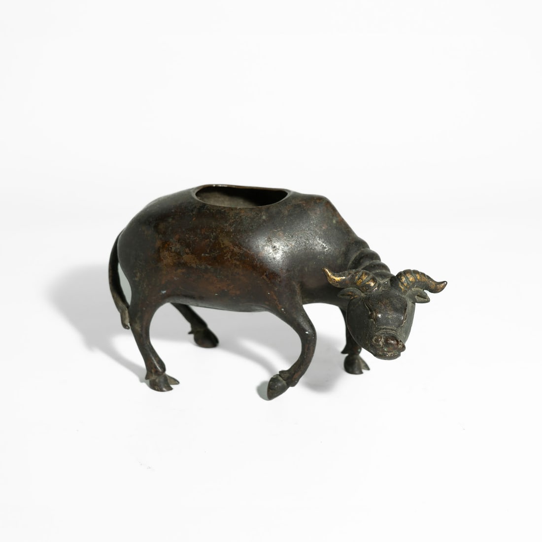 A Fine Heavy-cast Bronze Figure Of A Water Buffalo China, 17th – 18th Century: The heavy-cast bronze figure is naturalistically modelled as a recumbent water buffalo. The animal is depicted with its head slightly turned to the left, featuring large expressive eyes and powerful, 