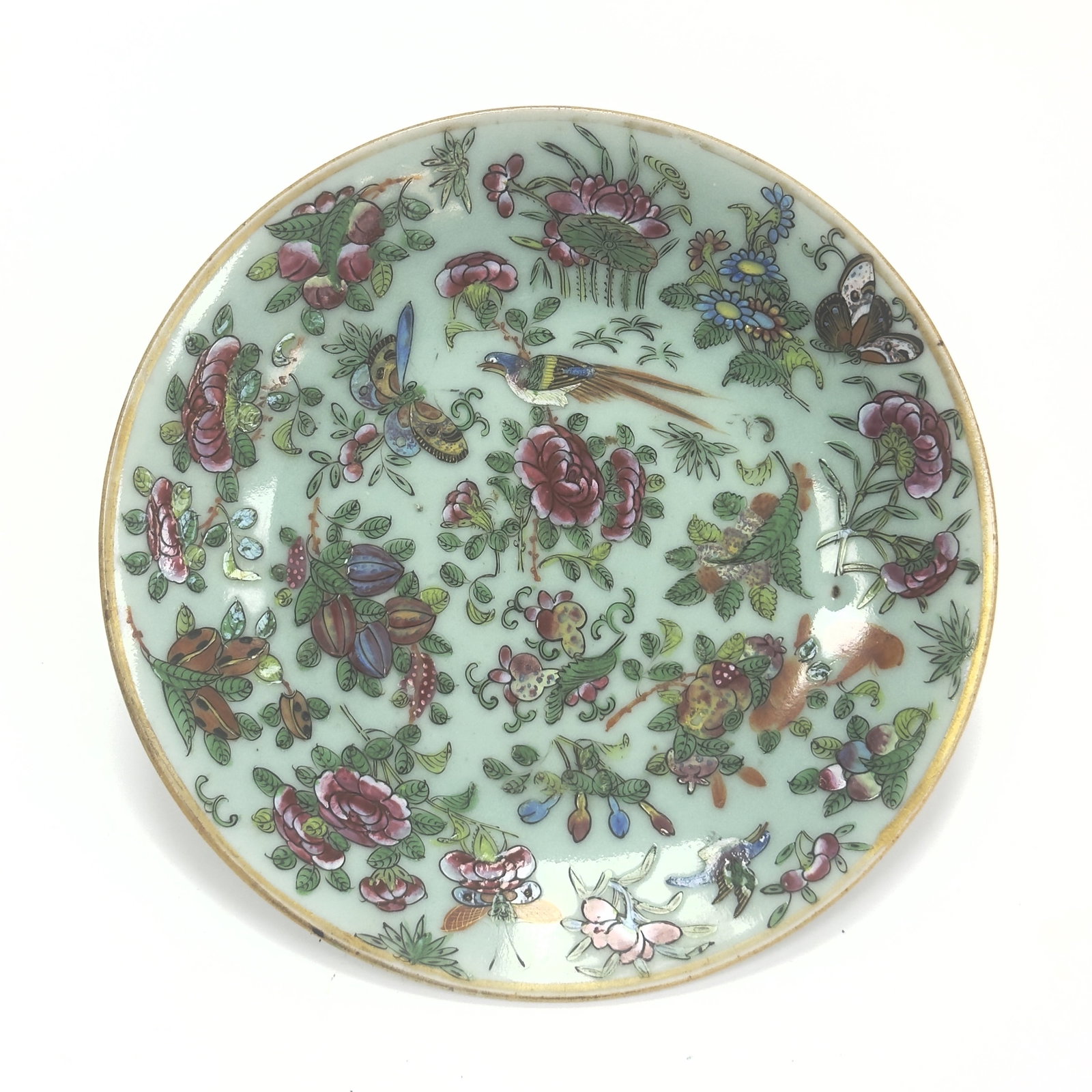 A Fine Celadon-ground 'Famille Rose' Plate China, Qing Dynasty, 19th century: This porcelain plate is uniquely decorated on a pale sea-green celadon-glazed ground, providing a sophisticated backdrop for the vibrant famille rose enamels. The central medallion is meticulously pai