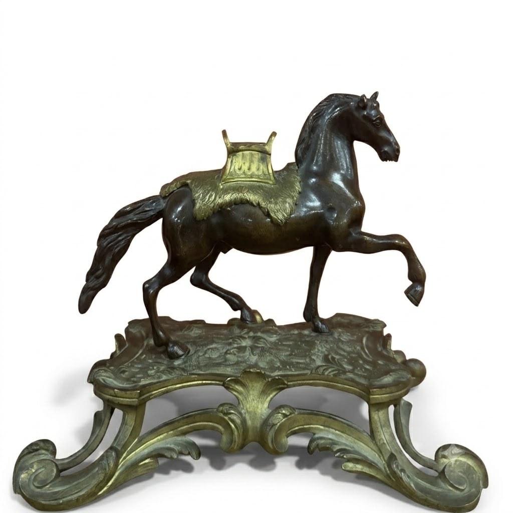 A cast and patinated gilt-bronze of a horse Possibily Portugal, 18th Century: The horse with a translucent brown patina, fitted with a chased and gilt-bronze saddle, raised on a chased and gilt-bronze base of Rocaille form.This decorative object is a fine example of 18th-centur