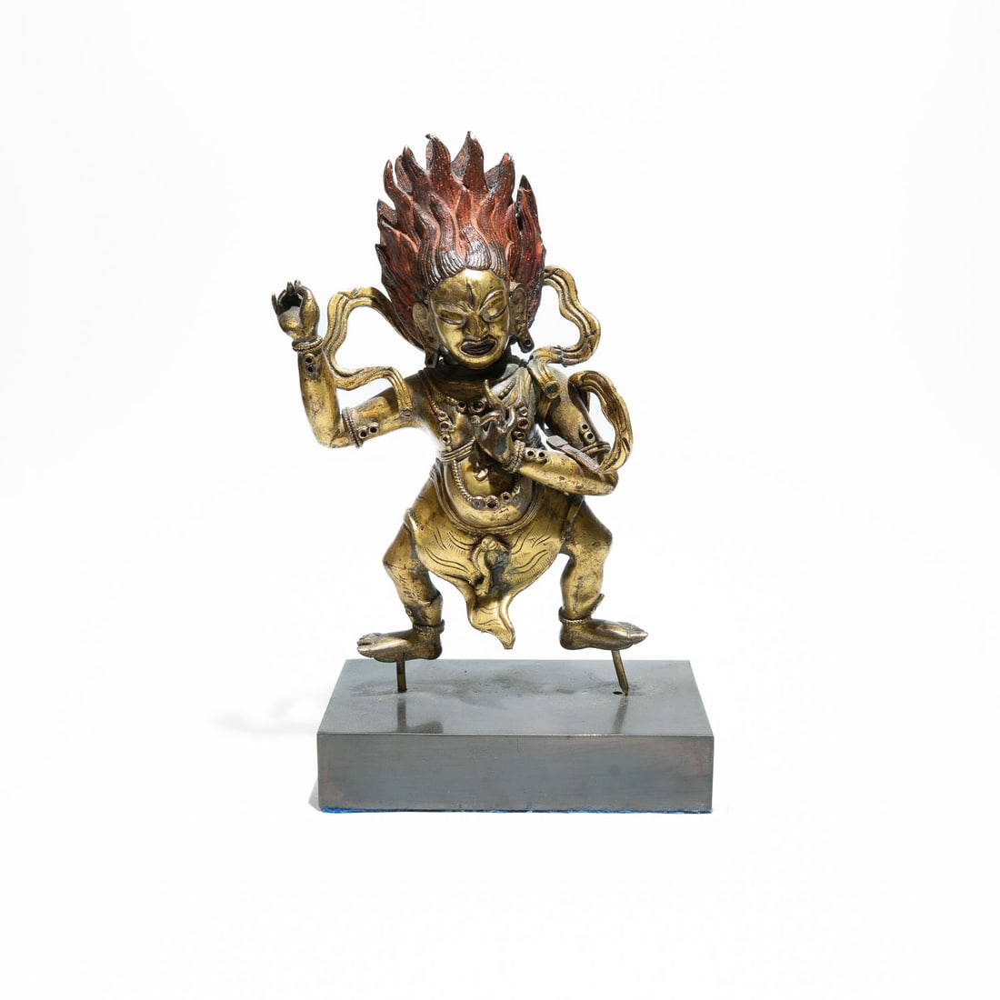A gilded copper alloy figure of the Wrathful Deity, Vajrapani 18th Century, Tibet: The face displays a fierce look, often featuring a third eye in the center of the forehead and exposed fangs to symbolize the destruction of ignorance.The hair rises vertically in reddish or orange to