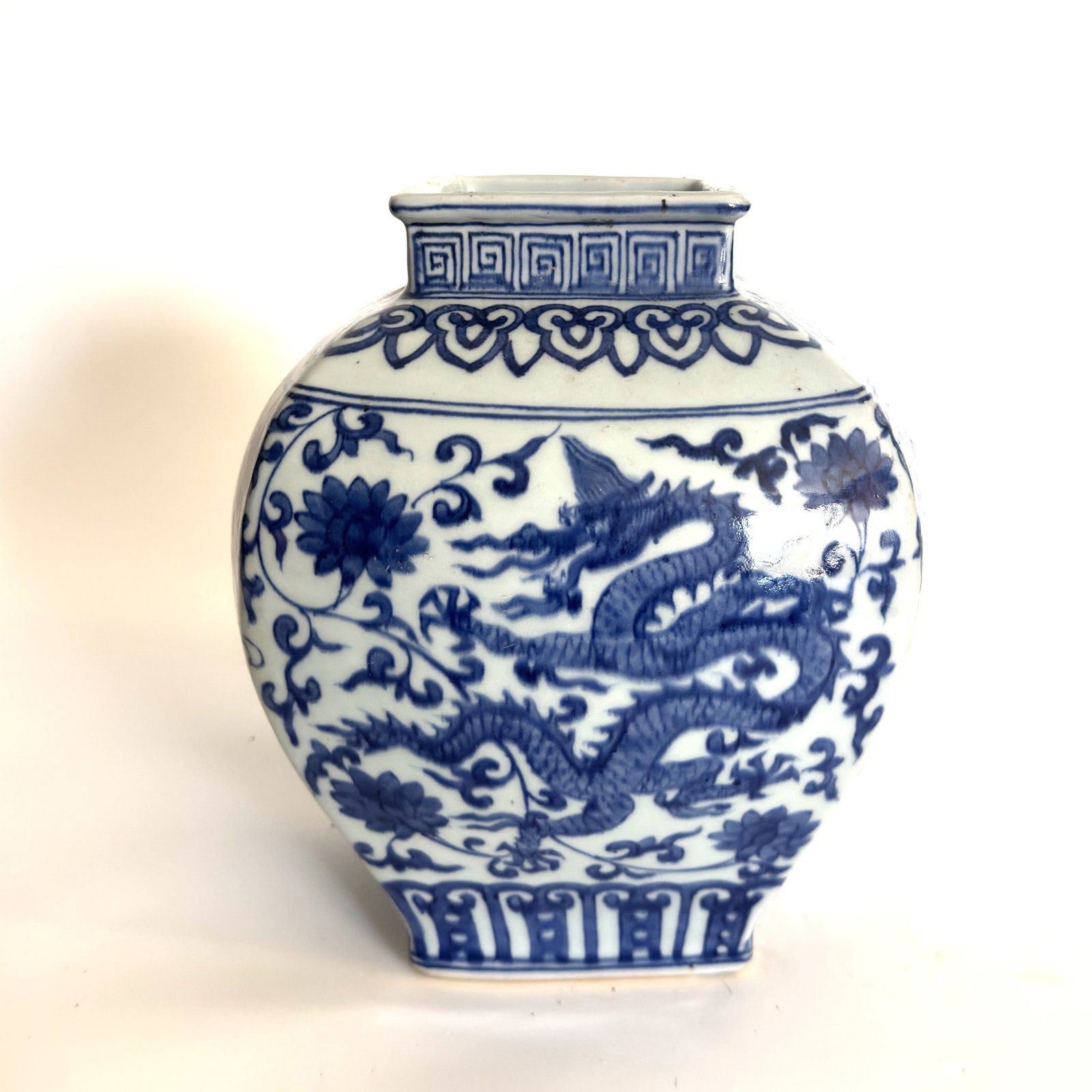 A Blue and White Quadrangular Dragon Vase China, Jiajing Mark (1522–1566): An porcelain vase of square section, finely painted with underglaze cobalt blue decoration.The four main faces are decorated with sinuous imperial dragons moving amidst dense scrolls of blossoming lot