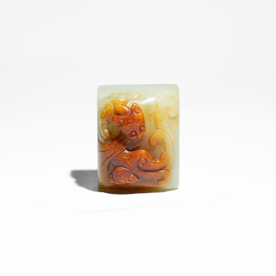 A carved Pale Celadon Jade Archaistic Seal China, Republic Period (1912–1949) or Earlier: A highly attractive pale celadon jade seal of rectangular form, carved with a low-relief archaistic design on the top surface.The carving cleverly utilizes a vibrant, rich layer of natural iron-russet