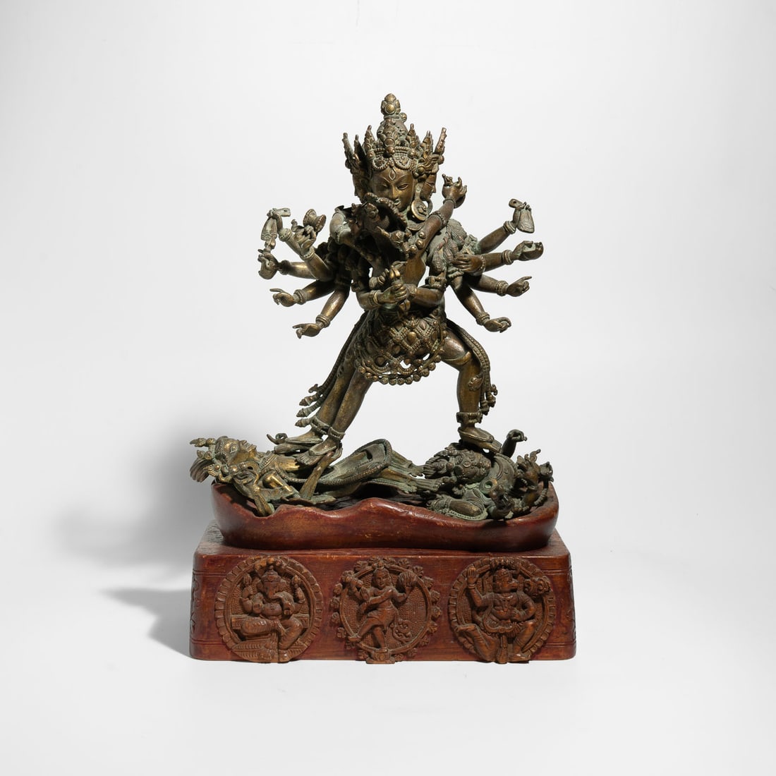 A Cast Gilt Bronze Group of a Wrathful Deity in Union (Yab-Yum) Sino-Tibetan, 18th – 19th: A cast gilt bronze sculpture of a multi-armed wrathful deity standing in alidhasana (trampling posture). The central figure is depicted in divine union (