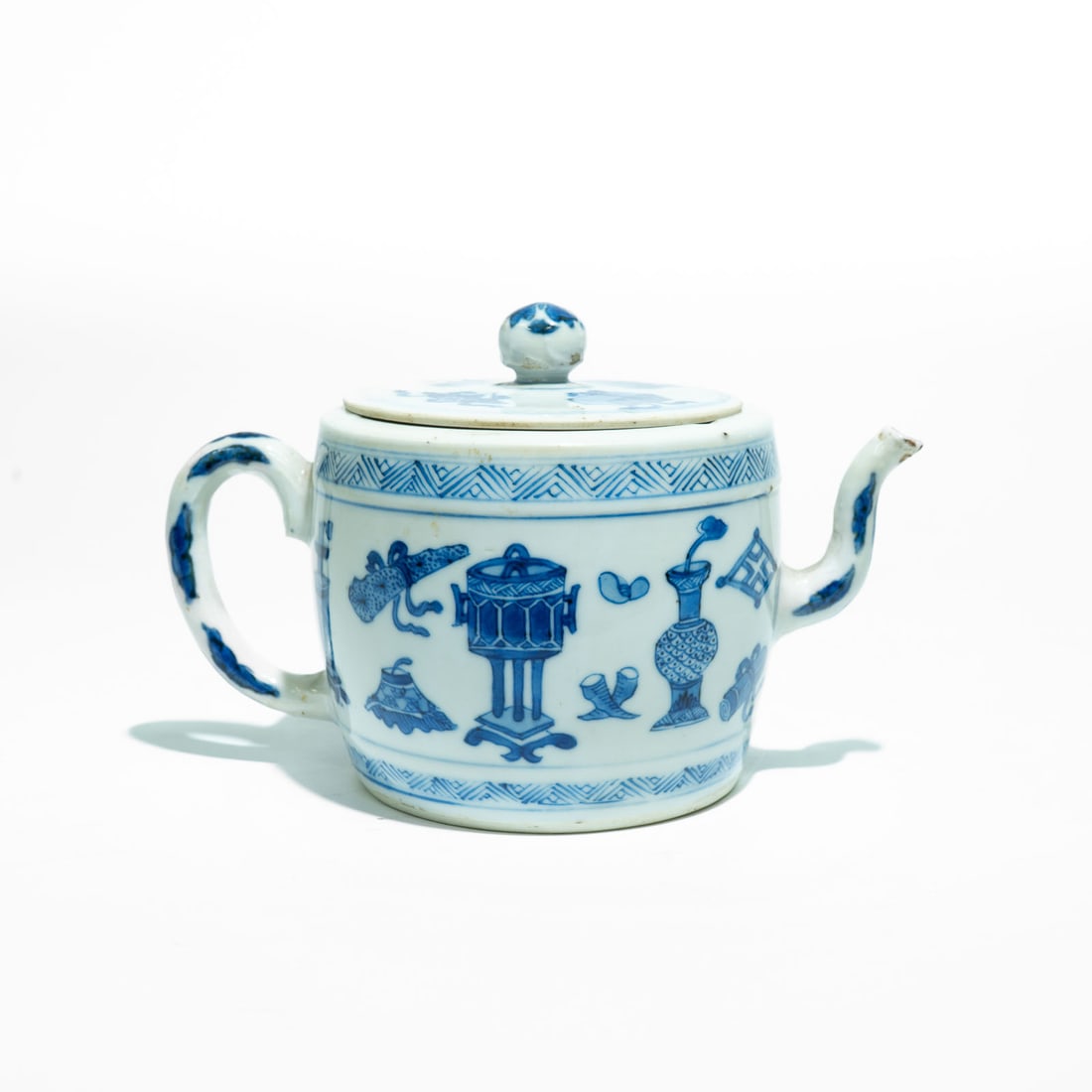 A Blue and White "Precious Objects" Teapot China, Qing Dynasty, Kangxi Period (1662–1722): A charming blue and white porcelain teapot of cylindrical form, featuring a short curved spout and a sturdy loop handle.The main body is painted in vibrant tones of underglaze cobalt blue with the "Hu