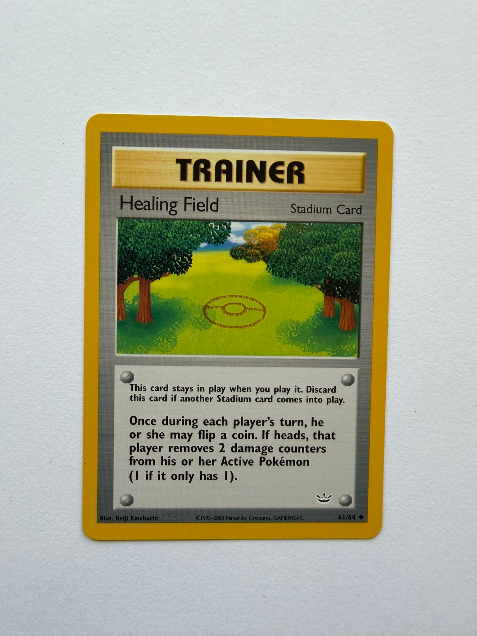 2000 Pokemon Healing Field 61/64 Neo Revelation: Healing Field 61/64 Stadium Trainer card from the 2000 Neo Revelation expansion. Unlimited non-holo card featuring Keiji Kinebuchi artwork. Ungraded with visible age-related wear. Please review photog