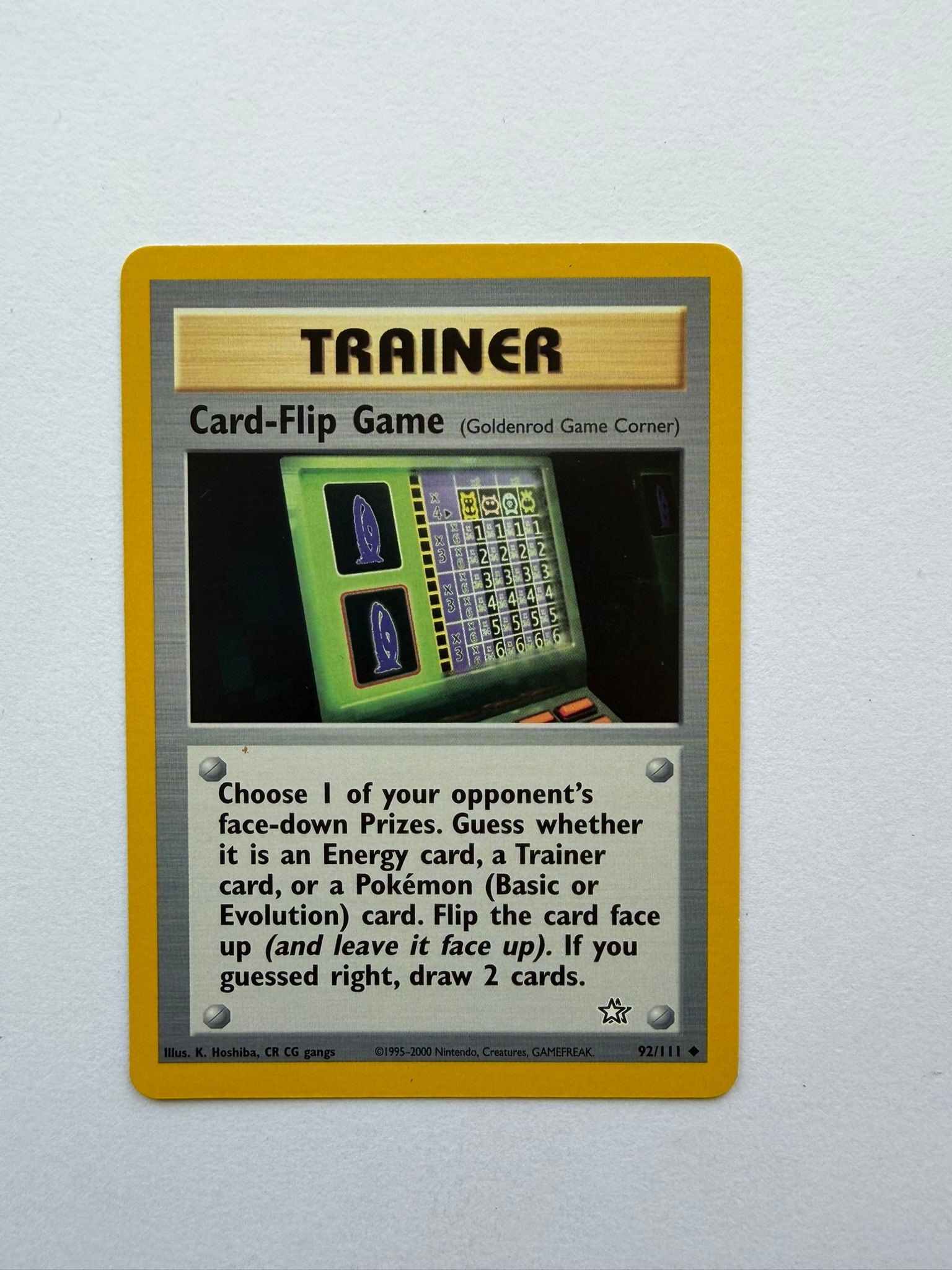 2000 Pokemon Card-Flip Game 92/111 Neo Genesis: Card-Flip Game 92/111 Trainer card from the 2000 Neo Genesis expansion. Unlimited non-holo card featuring the Goldenrod Game Corner. Ungraded with visible edge and surface wear.