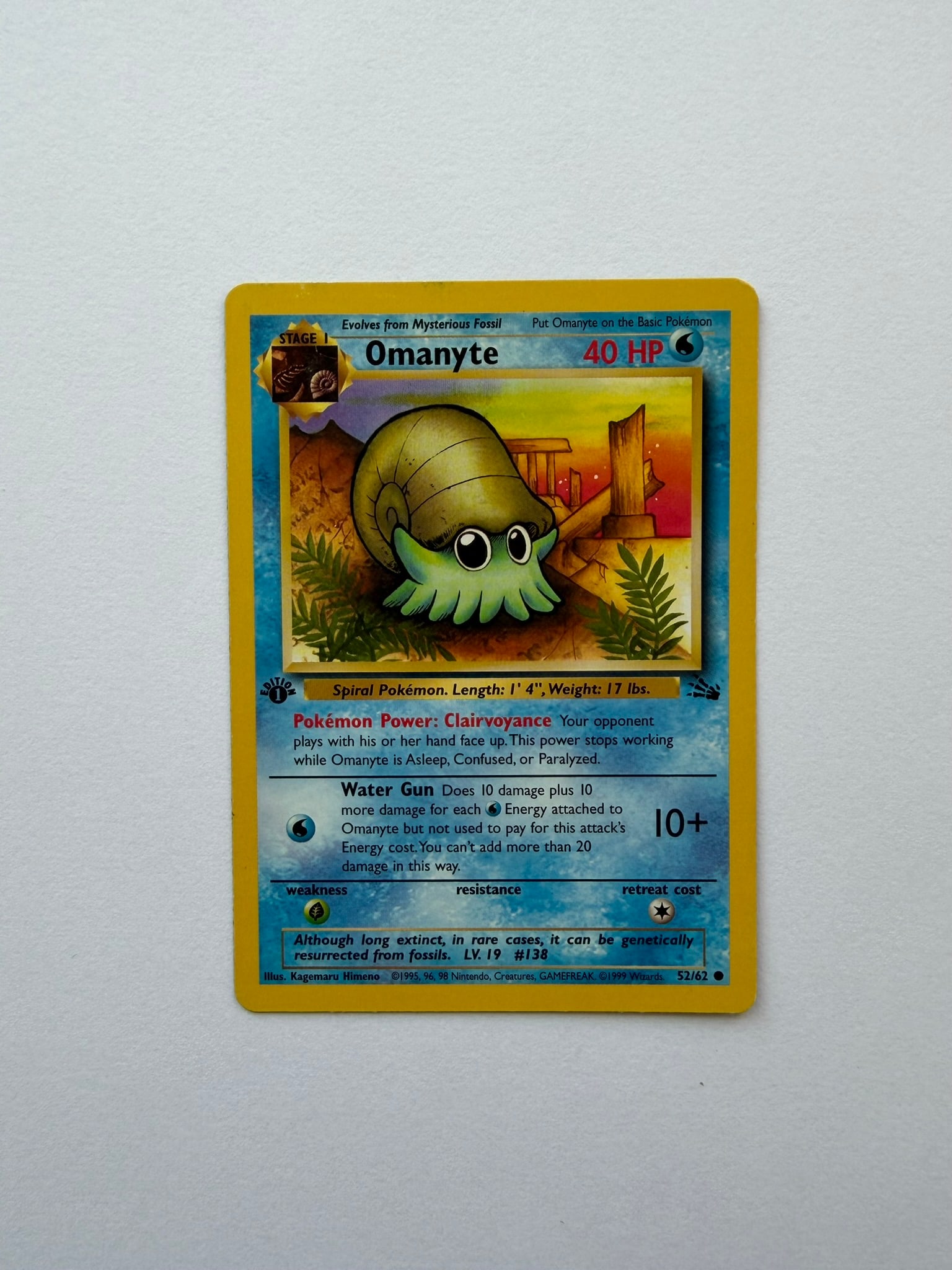 1999 Pokemon Omanyte 52/62 Fossil 1st Edition: Vintage Omanyte 52/62 from the 1999 Pokemon Fossil expansion. English 1st Edition common featuring artwork by Kagemaru Himeno. Ungraded with visible age-related edge and surface wear. Please review ph