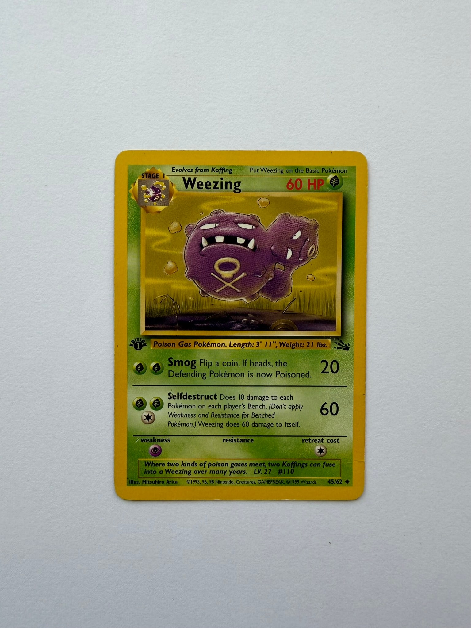 1999 Pokemon Weezing 45/62 Fossil 1st Edition: Vintage Weezing 45/62 from the 1999 Pokemon Fossil expansion. English 1st Edition non-holo uncommon featuring classic Mitsuhiro Arita artwork. Ungraded with visible edge and surface wear. Please revie
