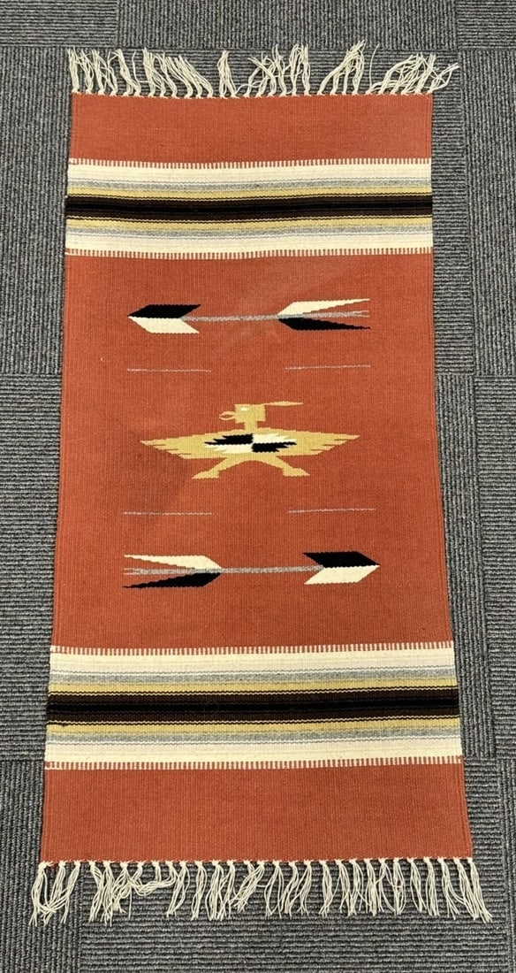 Chimayo Thunderbird Hand-Woven Table Runner, ca. 1970, 41 in: Hand-woven Chimayo table runner dating to circa 1970, featuring a rust-colored field with stylized Thunderbird and arrow motifs. The design incorporates dark brown, black, gray, golden tan, light tan,