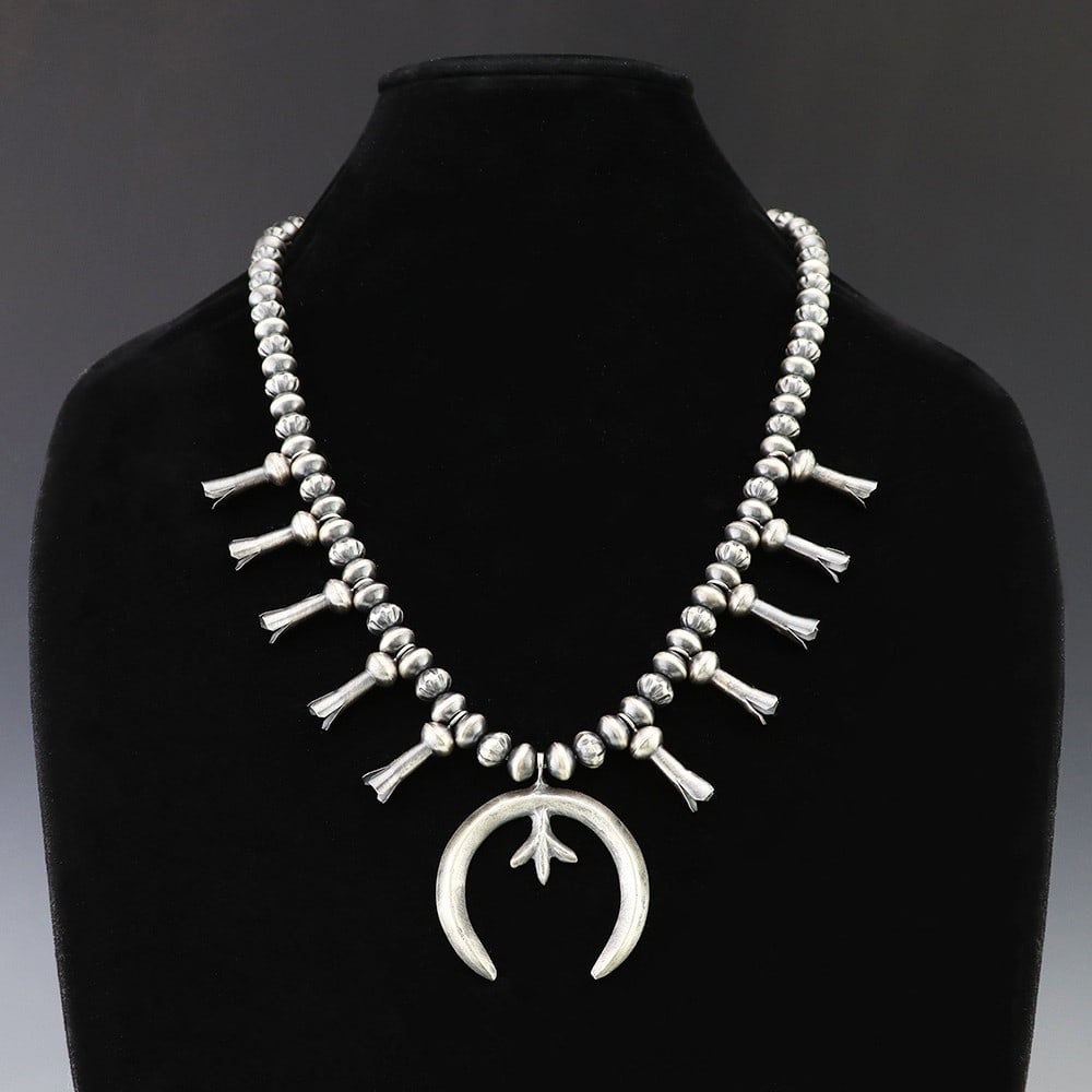 Navajo Sterling Silver Squash Blossom Necklace by Austin Haley: Navajo sterling silver squash blossom necklace by artist Austin Haley. The necklace features 9 mm sterling silver beads, a satin finish, sterling silver squash blossom elements, a naja pendant, and a 