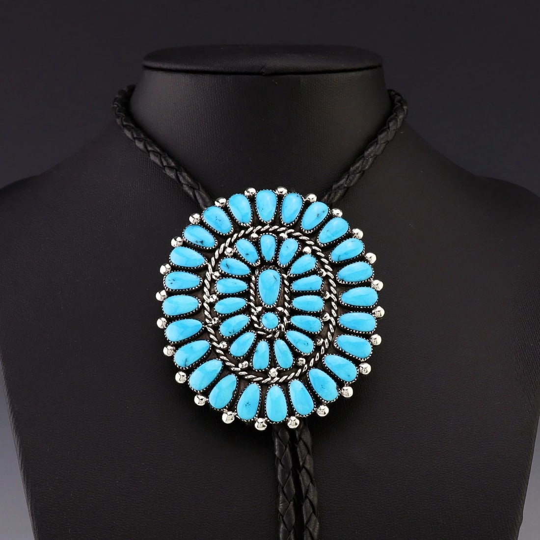 Lorraine Waatsa Zuni Turquoise Cluster Bolo Tie, Sterling Silver: Native American Zuni bolo tie attributed to Lorraine Waatsa, featuring a round turquoise cluster centerpiece mounted in a sterling silver setting with braided black bolo cord and sterling silver
