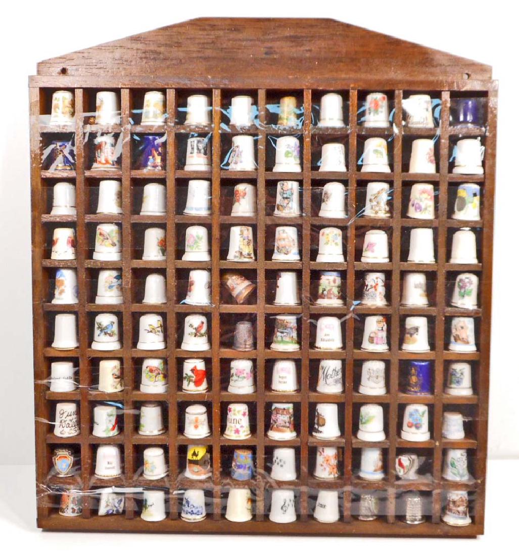 LOT OF 100 VINTAGE THIMBLES ON WOODEN THIMBLE SHELF: Thimbles are souvenirs from different States and a lot of various Bird and other thimbles. Shelf is 14" by 16"