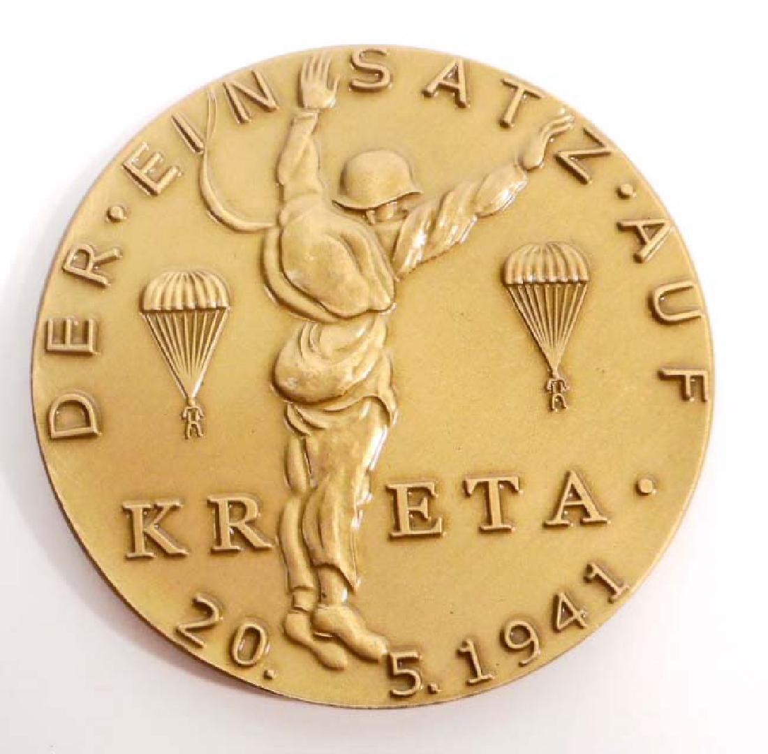 GERMAN NAZI LUFTWAFFE KRETA PARATROOPER FALLSCHIMJAGER: Measures 2 1/4" in diameter. The front reads 'Der - Einsatz - Auf Kreta 20.5.1941'. Has a paratrooper in the center with Two (2) in the back ground. The re-verse side reads 'Mit/JU 52/Unter - General 