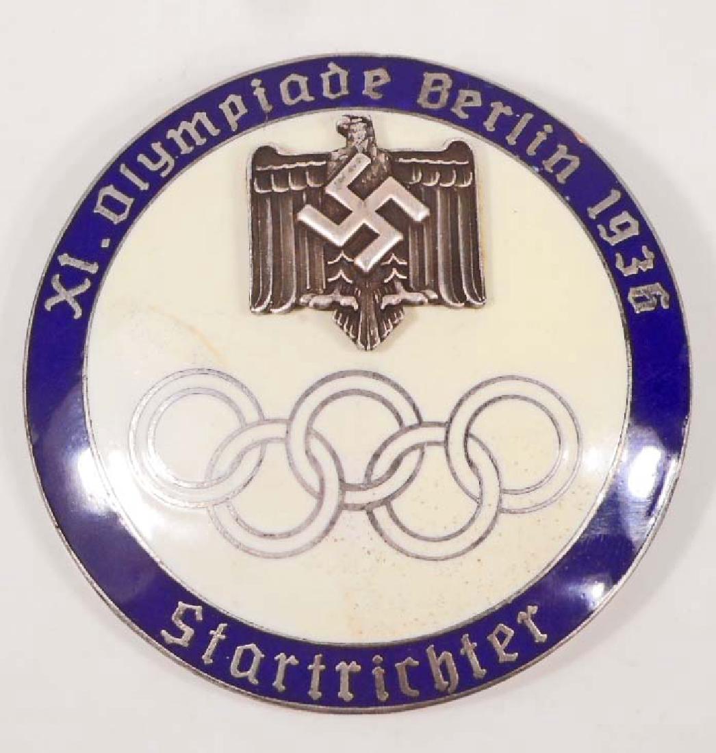GERMAN NAZI 1936 BERLIN SUMMER OLYMPICS STARTER BADGE: Measures 1 15/16" in diameter. The reverse side is maker marked 'ges gesch PJC'. Has a thin horizontal pin back. Two piece nickel construction with enamel.