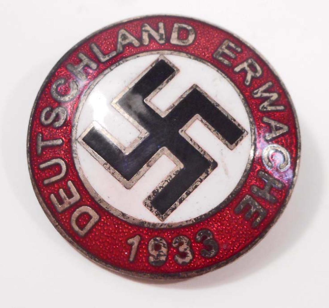GERMAN NAZI DEUTSCHLAND ERWACHE 1933 LAPEL PARTY BADGE: Measures 15/16" in diameter. The front reads 'Deutschland Erwache 1933'. Has a swastika in the center. The reverse side is maker marked 'RZM M1/129'. Has a thin horizontal safety pin back. Nickel cons