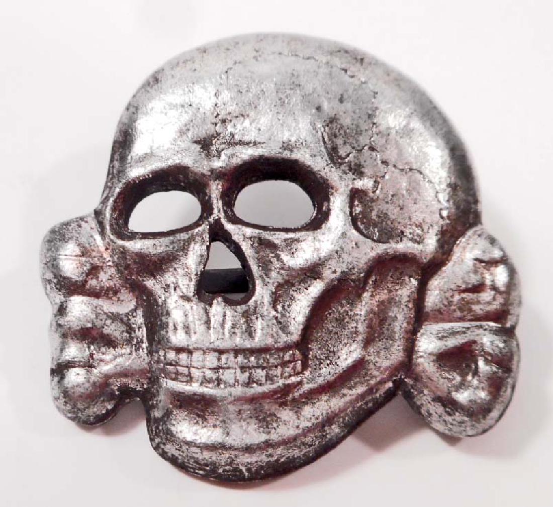 GERMAN NAZI WAFFEN SS OFFICERS VISOR CAP SKILL: . Measures 1 1/4" wide by 1 1/8" tall. The reverse side is maker marked 'RZM M1/52'. Has Two (2) flat horizontal prongs on the reverse side. Stamped silver plated nickel construction