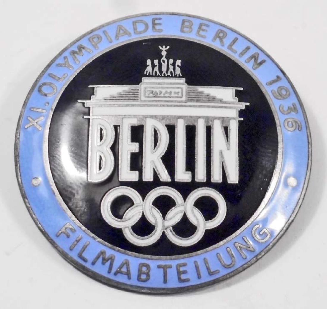 GERMAN NAZI 1936 BERLIN SUMMER OLYMICS FILM MAKER BADGE: Measures 1 1/2" in diameter. The reverse side is maker marked 'Rob Neff Berlin W 57'. Has a thin horizontal safety pin back. One piece nickel construction with light blue enamel