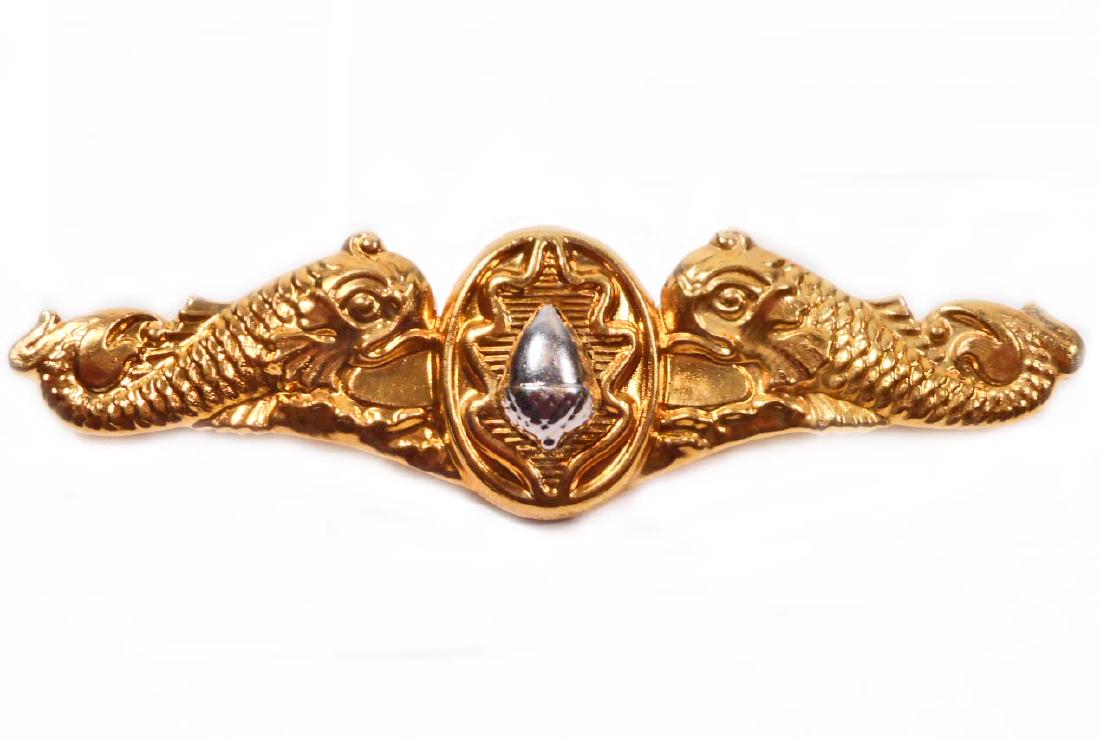 USN NAVAL SUBMARINE SURGEON DOLPHIN OFFICERS BREAST: Measures 3" wide by 3/4" tall. The front shows an acorn with an oak leaf in the back ground flanked by a dolphin on each side. The reverse is unmarked. Has a thin horizontal pin back with a locking ca