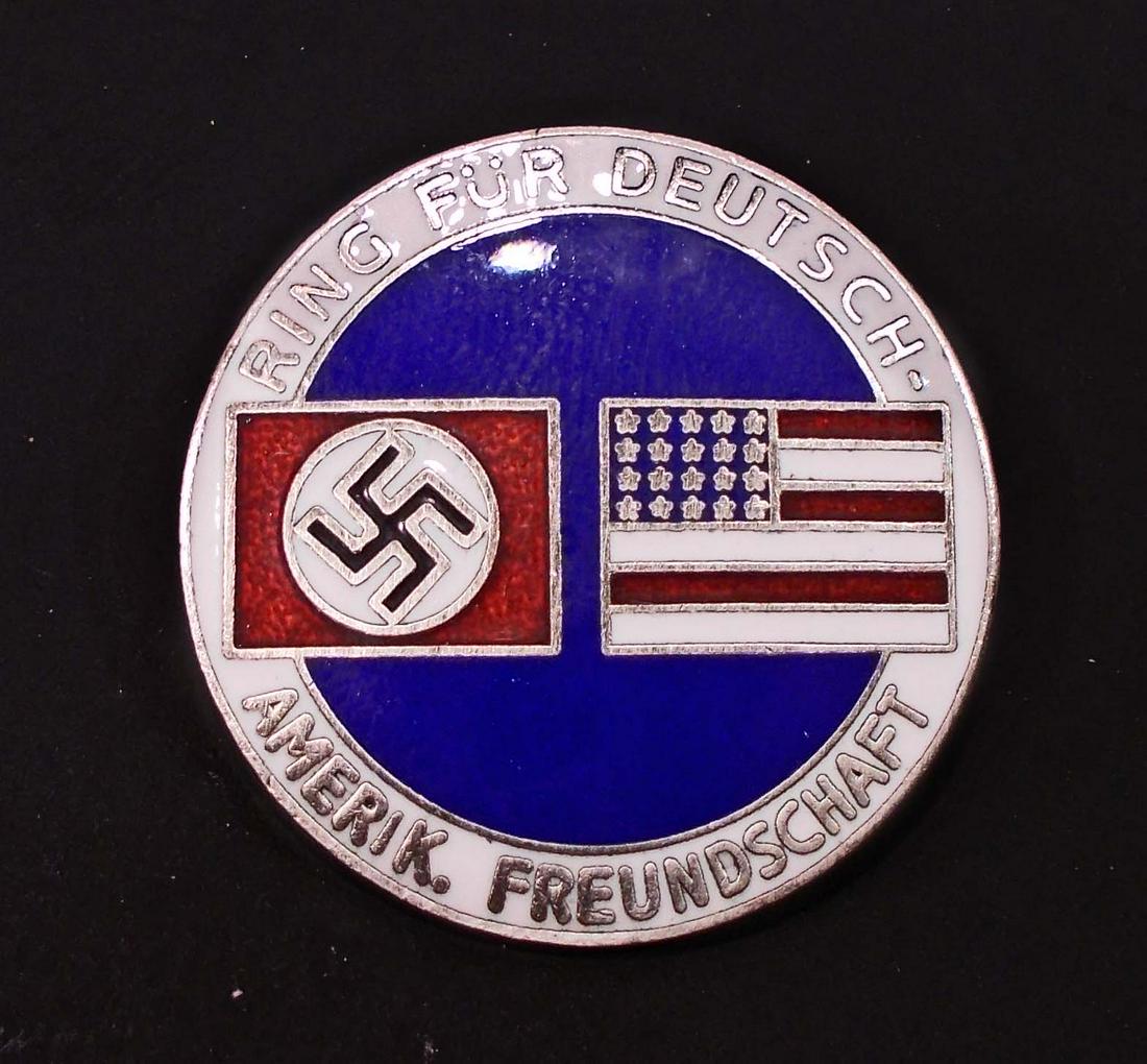 GERMAN AMERICAN BUND ENAMELED MEMBERSHIP BADGE: Front reads Ring Fur Deutsch Amerik Freundschaft. Has a swastika flag and an American flag in the center. Reverse side is maker marked CTD. Thin horizontal safety pinback. Nickel construction with ena