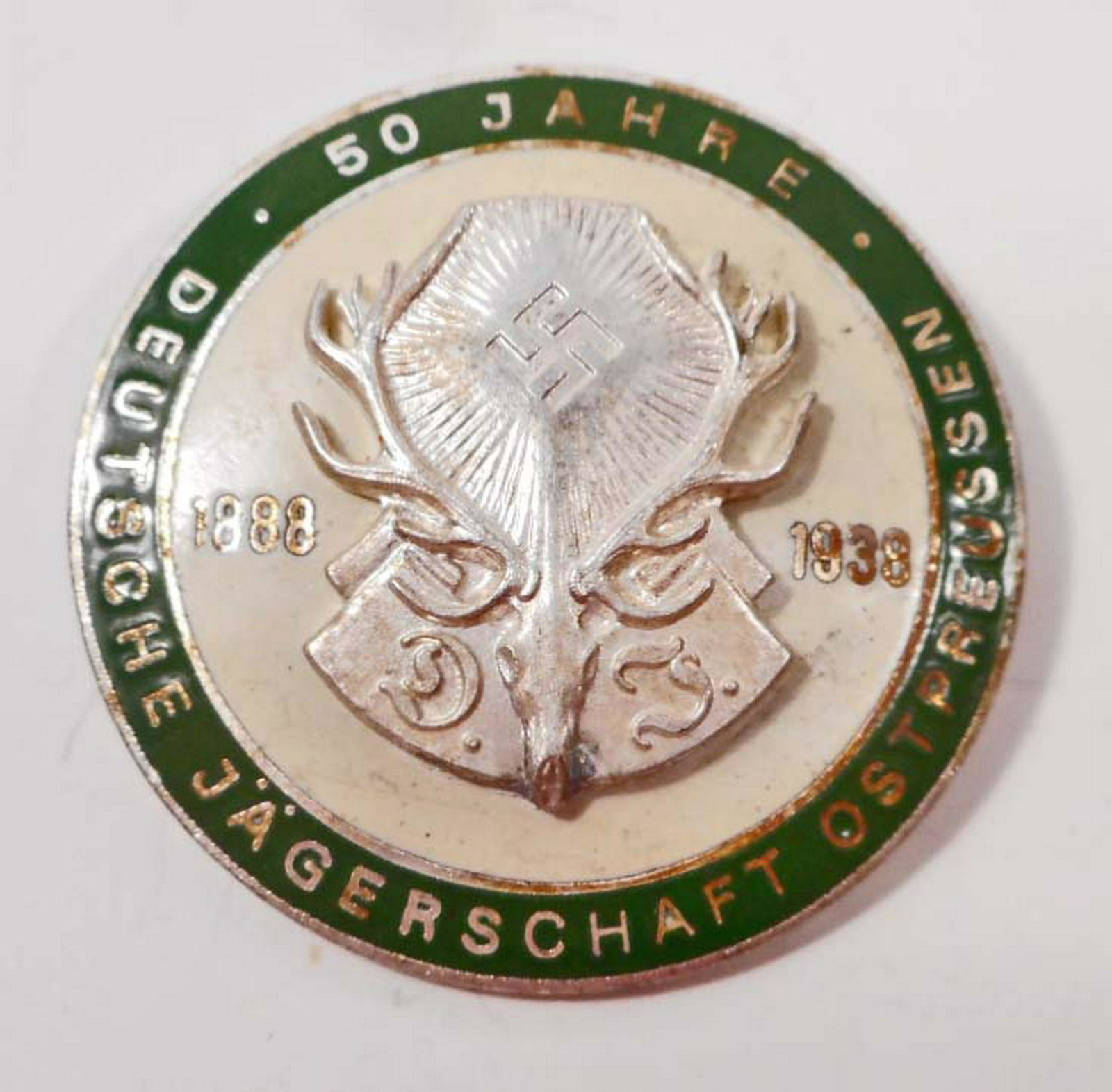 GERMAN 50 YEAR 1888-1938 HUNTING ASSOCIATION DEUTSCHE: . Measures 1 9/16" in diameter. The front reads '1888 - 1938 50 Jahre Deutsche Jagerschaft Ostpreussen'. Has the DJ deer with a pair of antlers in the center. The reverse side is maker marked 'H Werns