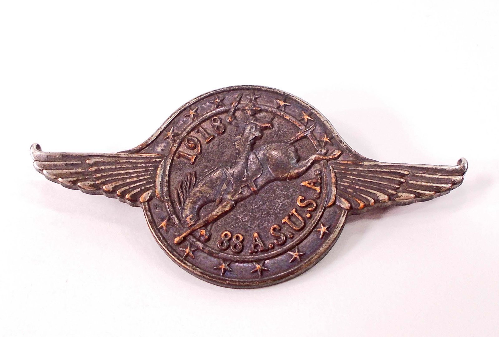 US WW1 1918 AEF 88TH AERO AVIATION SQUADRON BADGE: Measures 2 1/4" wide by 1 1/16" tall. The front reads '1918 88 A. S. U.S.A.'. The center shows a cowboy riding a bucking bronco horse with wings flanking each side. Has a thin horizontal pin back with